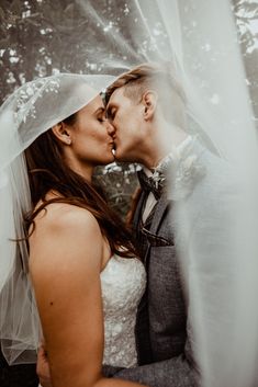 a bride and groom kissing under a veil