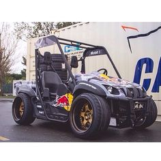 an electric golf cart is parked in front of a cargo truck with the word gard painted on it