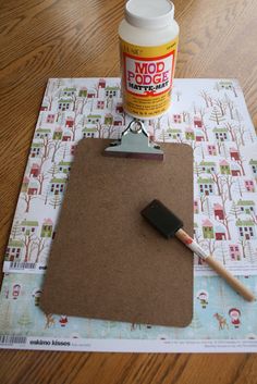 a clipboard with a paint brush on top of it next to a glue bottle