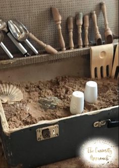 an old suitcase is filled with sand and utensils