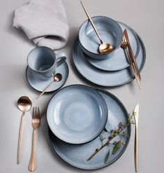 the table is set with blue dishes and gold utensils