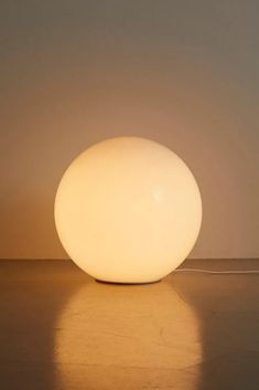 a large white ball light sitting on top of a wooden floor next to a wall