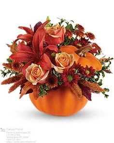 an orange pumpkin filled with flowers and greenery