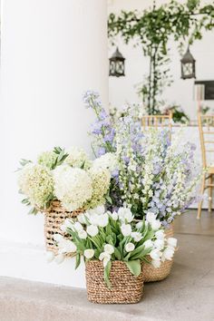 two baskets filled with flowers sitting on top of a floor next to a table and chairs