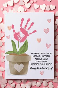 a greeting card with a handprinted flower in a pot and hearts around it