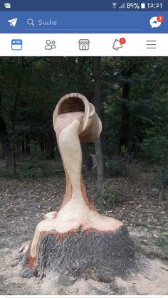 a wooden sculpture sitting on top of a tree stump in the middle of a forest