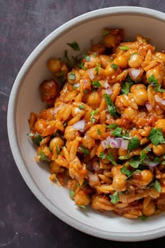 a white bowl filled with pasta and garnished with cilantro, red onions and parsley