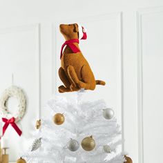 a stuffed dog sitting on top of a white christmas tree