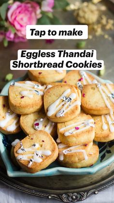 a plate full of cookies with icing on them and pink flowers in the background