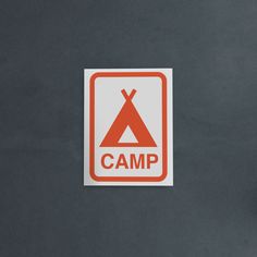 an orange and white sticker with the word camp on it in front of a gray background