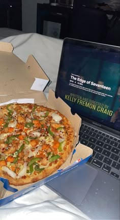 a pizza sitting on top of a laptop computer next to a box with the lid open