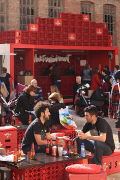 people sitting at tables in front of red crates