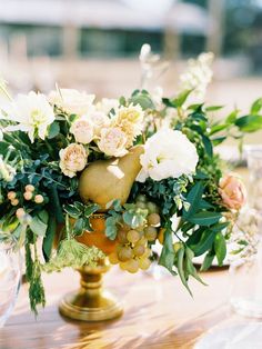 a vase filled with flowers sitting on top of a wooden table next to wine glasses