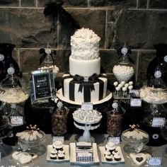 a black and white wedding cake surrounded by desserts