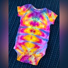 a baby bodysuit that has been dyed with multicolored tie - dye on it