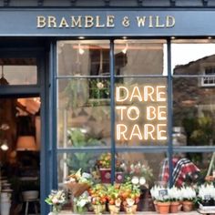 a store front with flowers and plants in the window that says dare to be rare