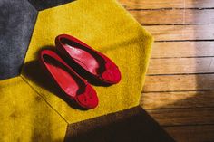 two pairs of red shoes sitting on top of a yellow and black carpeted floor