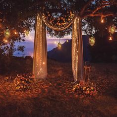 an outdoor wedding setup with candles and flowers on the ground under a tree at night