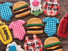 decorated cookies with baby ones and burgers on them sitting on top of a wooden table