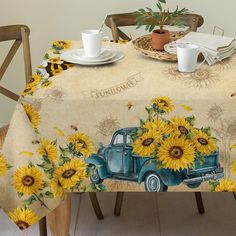 a table topped with a blue truck covered in sunflowers next to two cups and saucers