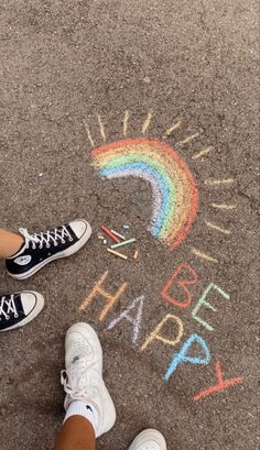 two people standing in front of a sidewalk with chalk writing on it and a rainbow