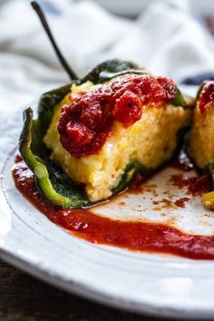 a white plate topped with stuffed peppers covered in sauce