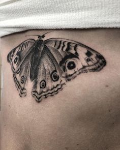 a butterfly tattoo on the side of a woman's stomach, with an eyeball