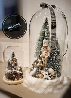 two snow globes sitting on top of a table next to each other with christmas decorations in them