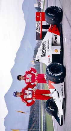 two people standing next to a race car