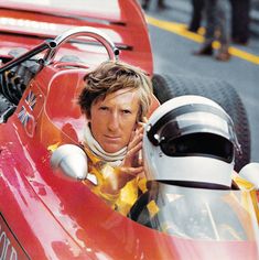 a man sitting in a race car with his hand on the steering wheel