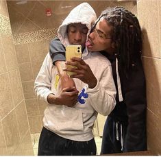 a man and woman taking a selfie in a bathroom mirror while holding a cell phone