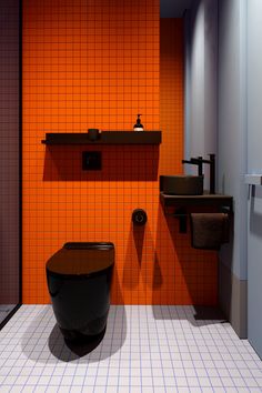 a bathroom with orange and black tiles on the walls