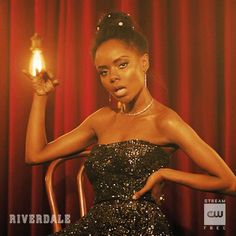 a woman sitting in a chair holding a lit candle up to her face with the words riverdale written on it