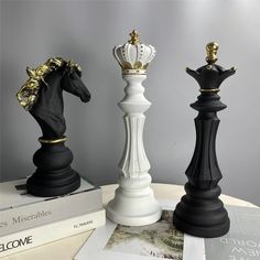 three black and white chess pieces sitting on top of each other next to some books