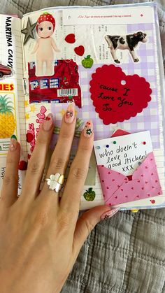 a woman's hand holding onto an open book with stickers and magnets on it