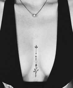 a black and white photo of a woman's chest with an arrow tattoo on it