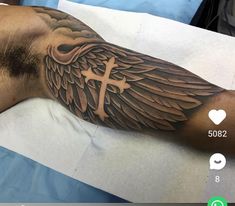 a man with a cross and wings tattoo on his arm