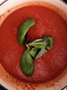 a pot filled with red sauce and green leaves