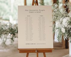 an easel with a seating chart on it and flowers in the background at a wedding