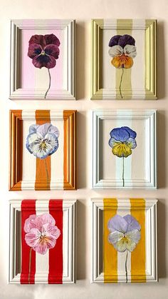 four framed pictures with flowers painted on them in different colors and sizes, hanging on the wall