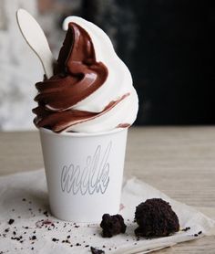 an ice cream sundae with chocolate toppings in a paper cup on a napkin