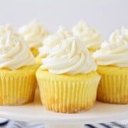 cupcakes with white frosting on a cake plate