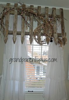 a window with white curtains and wooden sticks hanging from it's rodulage