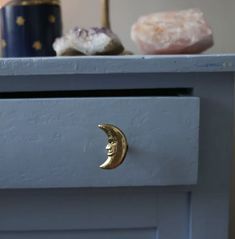 a blue dresser with a gold moon knob on the drawer and doughnuts in the background