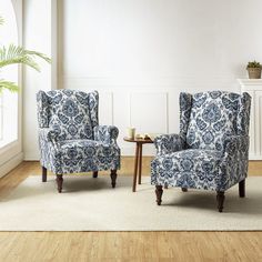 a living room with two blue chairs and a coffee table on the floor in front of a white wall