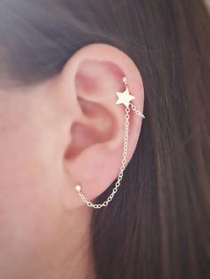 a woman wearing a star and chain ear cuff