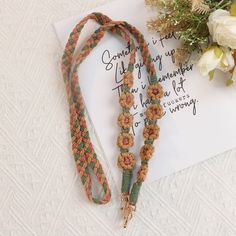 a couple of necklaces sitting on top of a piece of paper next to flowers