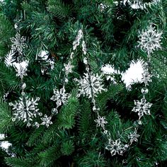 snowflakes are hanging from the branches of a pine tree