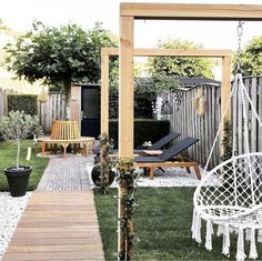 a backyard with a swing chair, hammock and wooden deck in the grass