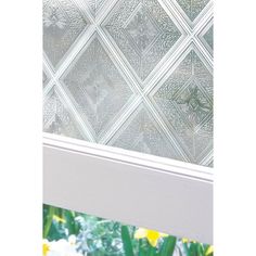 a window with some flowers in front of it and a glass block wall behind it